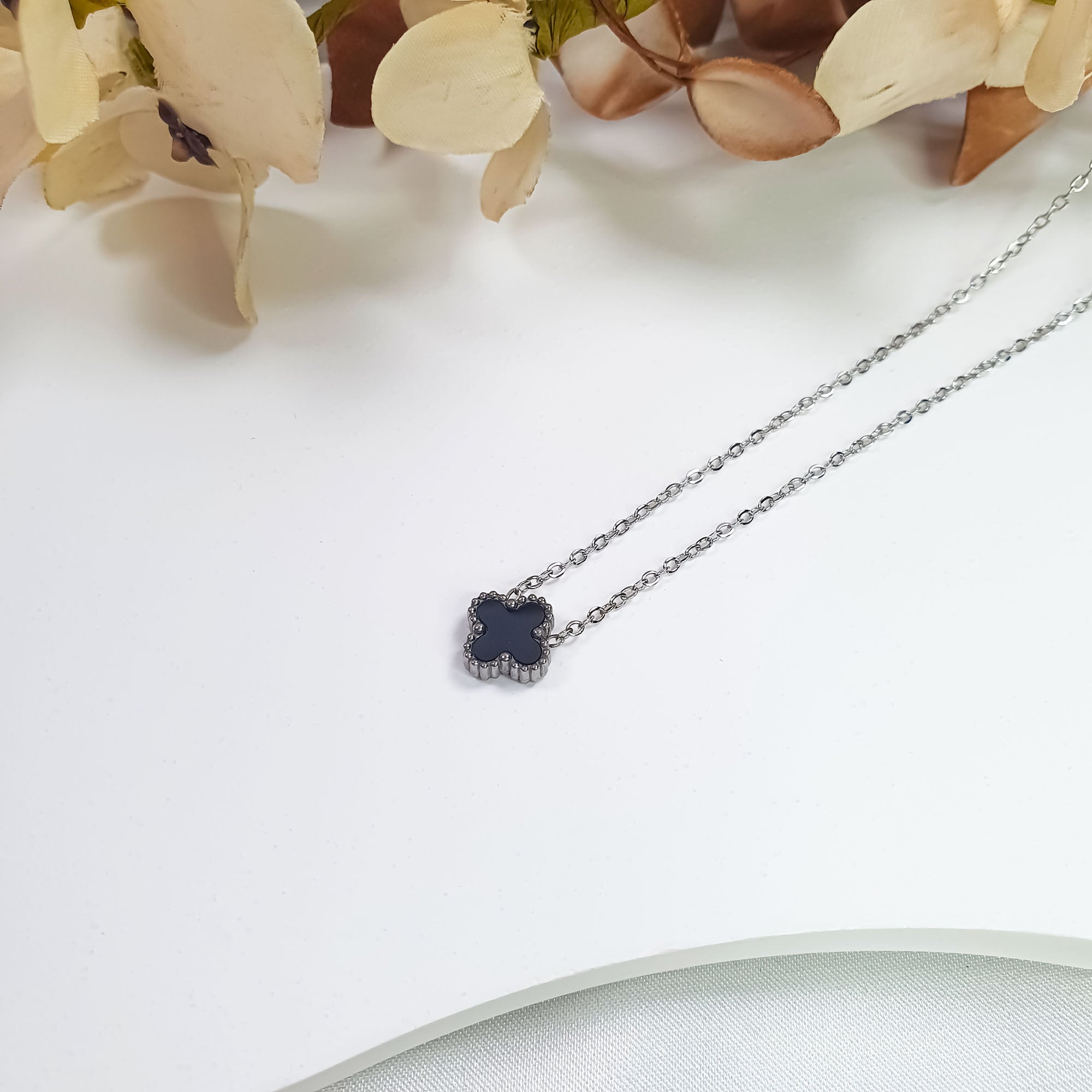 Kaklarota ar centrā novietotu melnu āboliņa detaļu