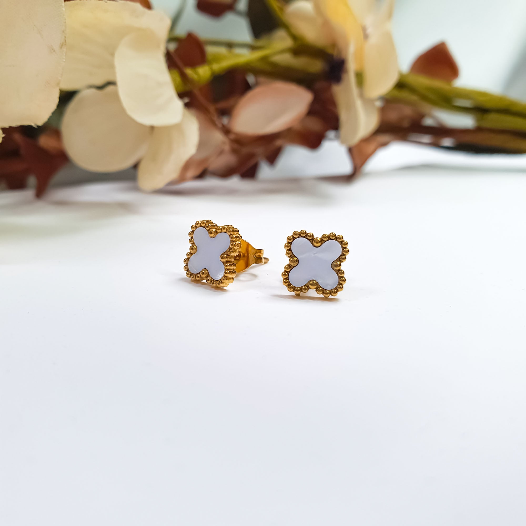 Zeltīta toņa auskari ar balta četrlapu siluetu